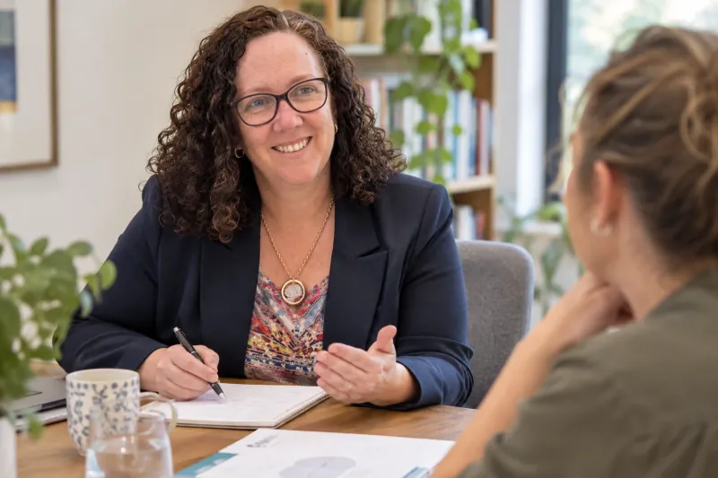 Dr Michelle Joosse in conversation at a table, taking notes